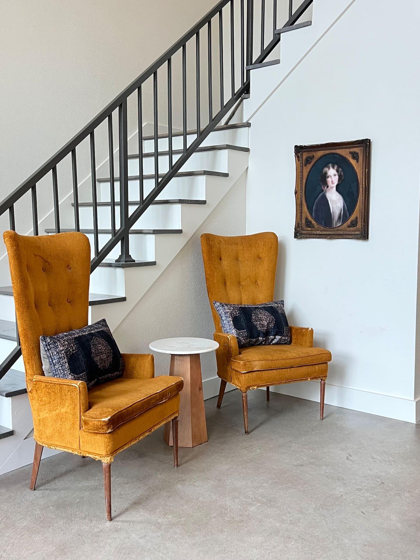 Living area with staircase and velvet chairs